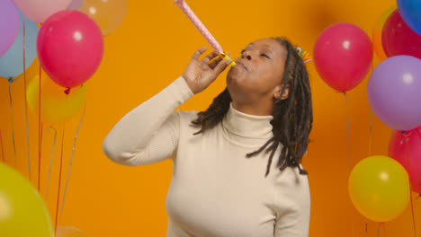 Studioporträt-Einer-Frau-Mit-Geburtstagsstirnband,-Die-Mit-Luftballons-Und-Partygebläse-Feiert